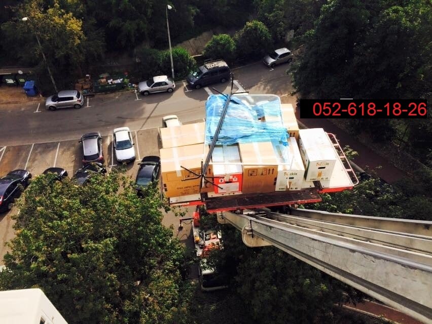 במהלך הובלת דירה עם מנוף - משאית עם מנוף הרמה מעבירה ארגזים היישר למרפסת בקומה גבוהה של דירה בראשון לציון